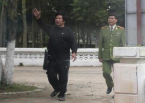 A policeman watches as Cu Huy Ha Vu (L) waves to his wife Duong Ha before their meeting at the Number 5 Prison in Thanh Hoa province, about 200 km (124 miles) south of Hanoi, in this picture taken from a car on February 24, 2012. CREDIT: REUTERS/STRINGER